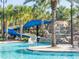 A waterpark slide with waterfalls surrounded by lush palm trees in a community pool area at 7184 Oakmoss Loop, Davenport, FL 33837