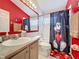 Bathroom with a vibrant red wall, Mickey Mouse accents, and a tub-shower combination at 8019 Indian Creek Blvd, Kissimmee, FL 34747
