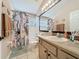 Bright bathroom features a tub with shower, floral curtain, a large mirror and a tiled floor at 8019 Indian Creek Blvd, Kissimmee, FL 34747
