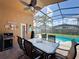 Screened patio with ceiling fan, dining table, grill, and view of the beautiful pool and backyard at 8019 Indian Creek Blvd, Kissimmee, FL 34747