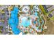 Aerial view of a resort-style community pool with slides, a lazy river, and lounging areas, surrounded by lush landscaping at 971 Paradise Dr, Davenport, FL 33897
