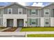 Charming townhome featuring a manicured lawn, symmetrical landscaping, and a stylish gray and white facade at 971 Paradise Dr, Davenport, FL 33897