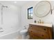 Bathroom features a shower and tub combo, a wood vanity with a white top, and a round mirror at 1047 Banks Rose St, Kissimmee, FL 34747