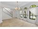 Large living room with tile floors, a modern chandelier, with staircase and three large windows at 1047 Banks Rose St, Kissimmee, FL 34747