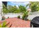 Brick patio area featuring lush landscaping, a white fence, and a covered grill at 1047 Banks Rose St, Kissimmee, FL 34747