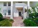 Exterior of a white building with a brick walkway, dark front door, and landscaped greenery at 1211 Celebration Ave # 102, Celebration, FL 34747