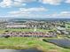 Beautiful aerial view of a neighborhood with red-tiled roofs and lush green golf course and large bodies of water nearby at 13136 Alderley Drive Dr, Orlando, FL 32832