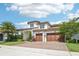 Charming two-story home with a three-car garage, complemented by lush landscaping and a beautiful brick driveway under a blue sky at 13136 Alderley Drive Dr, Orlando, FL 32832