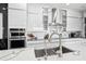 Close-up of a kitchen featuring a stainless steel sink, faucet, marble countertops, and modern appliances at 13136 Alderley Drive Dr, Orlando, FL 32832