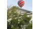 Bright hot air balloon floating over a house, partially obscured by lush trees at 204 Celebration Blvd, Celebration, FL 34747