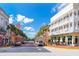 A scenic street lined with vibrant buildings, palm trees, and parked cars under a sunny sky at 204 Celebration Blvd, Celebration, FL 34747