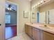 Bathroom featuring double sinks, cabinet storage and a bedroom view from the doorway at 2150 Emperor Dr., Kissimmee, FL 34744