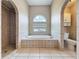 Bathroom showcasing tiled shower, large garden tub, and arched window for natural light at 2150 Emperor Dr., Kissimmee, FL 34744
