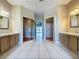Bathroom view showcasing double sinks, ceramic tile flooring, and dual mirrored closet doors at 2150 Emperor Dr., Kissimmee, FL 34744