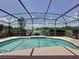 Outdoor pool surrounded by a screened enclosure and views of the backyard and lake at 2150 Emperor Dr., Kissimmee, FL 34744