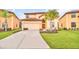Inviting two-story home featuring a terra cotta roof, two-car garage and mature palm trees at 2628 Tranquility Way, Kissimmee, FL 34746