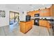 Spacious kitchen with wood cabinets, black appliances, and a granite island at 2628 Tranquility Way, Kissimmee, FL 34746