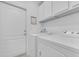 A clean laundry room with white washer and dryer, white door and white cabinets at 2628 Tranquility Way, Kissimmee, FL 34746