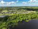 An aerial view of a suburban area featuring houses nestled among trees near a large body of water at 3138 Dark Sky Dr, St Cloud, FL 34773
