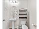 Elegant powder room featuring pedestal sink, oval mirror, modern lighting, and dark wood accents at 3138 Dark Sky Dr, St Cloud, FL 34773