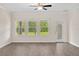 Spacious living room with wood-look floors, three large windows, and door to backyard at 3138 Dark Sky Dr, St Cloud, FL 34773