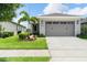 Inviting home exterior featuring a well-kept lawn, palm tree, and a neutral-toned facade with a two-car garage at 3428 Sagebrush St, St Cloud, FL 34773