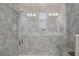 Close-up of a luxurious shower with a seat, multiple shower heads, and elegant gray stone tiling at 3428 Sagebrush St, St Cloud, FL 34773