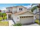 Two-story home featuring a spacious two-car garage, a well-kept lawn, and mature palm trees at 521 Rena Dr, Davenport, FL 33897