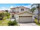 Two-story home featuring a spacious two-car garage, a well-kept lawn, and mature palm trees at 521 Rena Dr, Davenport, FL 33897