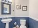 Stylish powder room with pedestal sink, decorative mirror, and two-tone wall design at 521 Rena Dr, Davenport, FL 33897