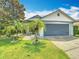 Charming home featuring a two-car garage, well-manicured lawn, and tropical palm trees at 550 Canary Island Cir, Davenport, FL 33837