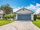 Charming home featuring a two-car garage, well-manicured lawn, and tropical palm trees at 550 Canary Island Cir, Davenport, FL 33837