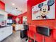 Red-themed kitchen boasts sleek countertops, white cabinets, and stylish bar seating area at 550 Canary Island Cir, Davenport, FL 33837