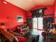 Red living room features a vaulted ceiling, black leather furniture and sliding glass doors at 550 Canary Island Cir, Davenport, FL 33837