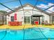The screened-in pool features an outdoor kitchen and a dining table with an umbrella for outdoor enjoyment at 550 Canary Island Cir, Davenport, FL 33837
