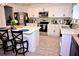 Well-lit kitchen with stainless steel appliances, white cabinetry, a functional island, and wood-look tile flooring at 673 Sarner Pass Way, Winter Haven, FL 33881