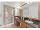 Well-lit bathroom with a glass-enclosed shower and double sink vanity with granite countertops at 7509 Mourning Dove Cir # 303, Reunion, FL 34747