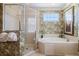 Bathroom with a corner bathtub, glass shower, and tropical-themed wallpaper at 7550 Gathering Dr, Reunion, FL 34747