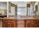Double vanity bathroom featuring granite countertops, wood cabinets, and tropical wallpaper at 7550 Gathering Dr, Reunion, FL 34747
