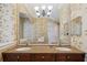 Double sink bathroom vanity with a large mirror, granite countertop and decorative wallpaper at 7550 Gathering Dr, Reunion, FL 34747