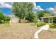 Expansive backyard with storage sheds, a well-manicured lawn, and mature trees at 906 Elm Forest Dr, Minneola, FL 34715