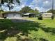 Property view featuring a well-maintained lawn, a two-car garage, and a carport on a sunny day at 930 Aultman Rd, Kissimmee, FL 34744