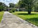 Brick home with lush green lawn, mature trees, and covered parking area on a sunny day at 930 Aultman Rd, Kissimmee, FL 34744