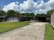 View of the detached two-car garage, home, and covered carport with long driveway at 930 Aultman Rd, Kissimmee, FL 34744