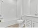 Bathroom showcasing white tiled tub with white vanity and toilet with neutral flooring at 983 Silverlake Blvd, Lake Alfred, FL 33850