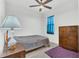 Bedroom featuring a comfortable bed, ceiling fan, wooden dresser and blue curtains at 983 Silverlake Blvd, Lake Alfred, FL 33850