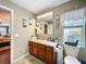 Bathroom featuring a wood vanity, a large mirror, and natural lighting at 1011 Dampierre Ct, Kissimmee, FL 34759