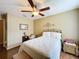 Well-lit bedroom with a ceiling fan, mirror, and decorative wall art complemented by hardwood floors at 1011 Dampierre Ct, Kissimmee, FL 34759