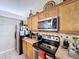 Efficient kitchen featuring stainless steel appliances, wooden cabinets, and decorative tile backsplash at 1011 Dampierre Ct, Kissimmee, FL 34759