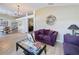 Cozy living room with purple sofas, stylish glass coffee table, and an open view to the dining area at 1011 Dampierre Ct, Kissimmee, FL 34759